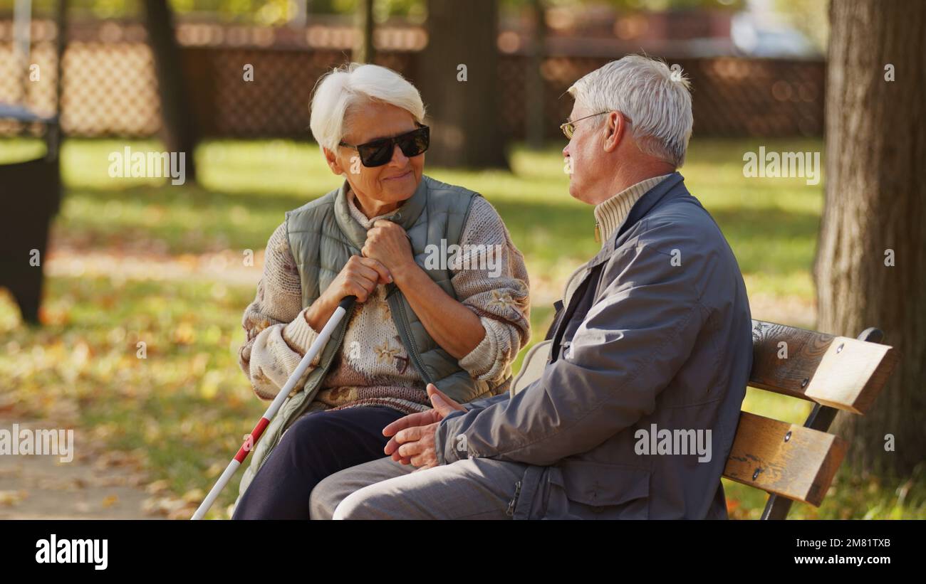 Donna anziana cieca con occhiali da sole scuri con il marito nel parco. Foto di alta qualità Foto Stock
