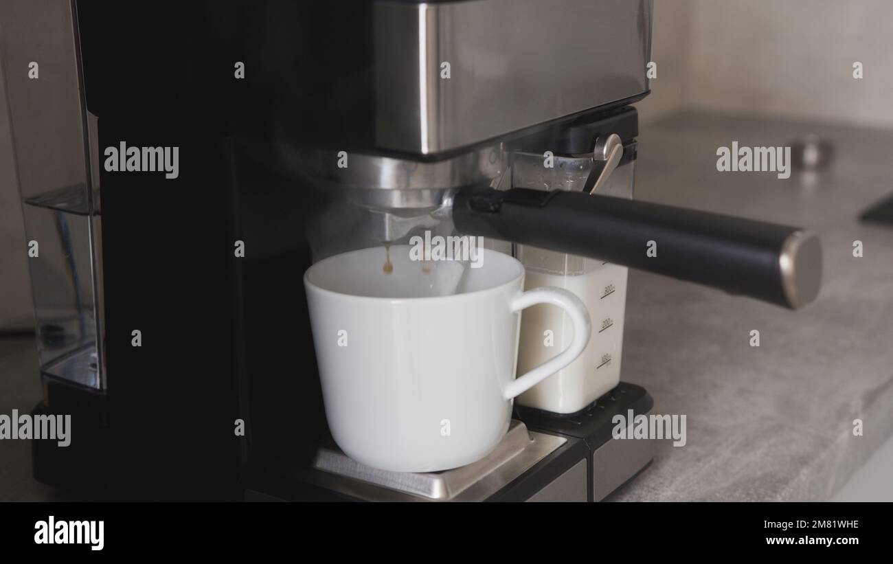 vista in primo piano del caffè caldo versato dal beccuccio, preparazione del caffè mattutino con macchina per il caffè. Foto di alta qualità Foto Stock