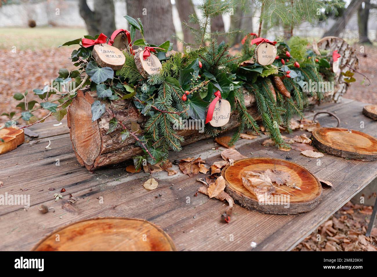 Un tavolo esterno è decorato con una corona di Natale e ambienti in legno. I bambini hanno scritto messaggi di speranza sulle decorazioni Foto Stock