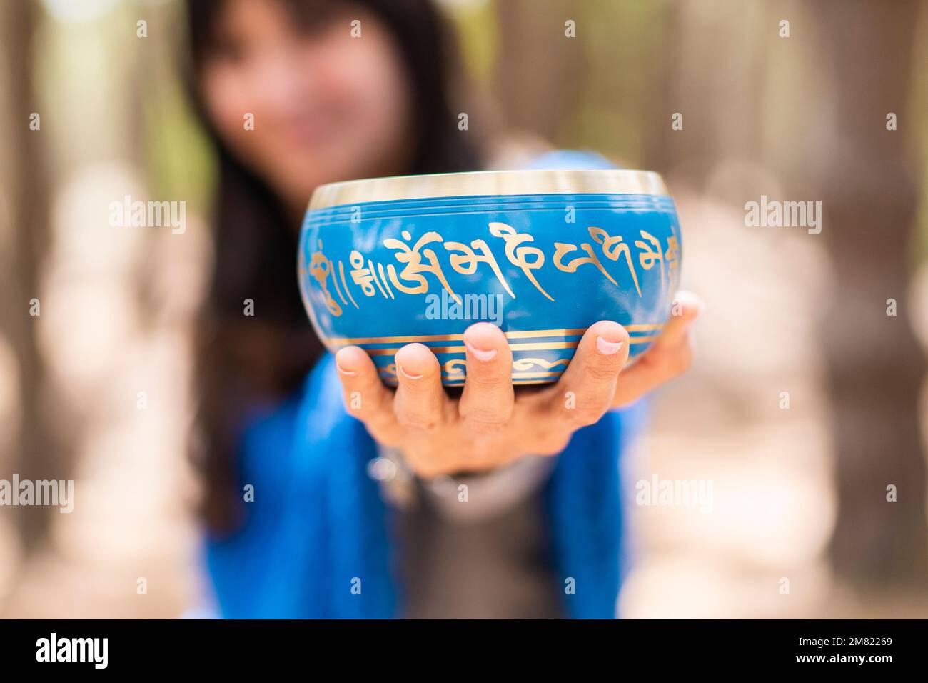 Una donna che tiene in mano una ciotola di canto tibetana Foto Stock