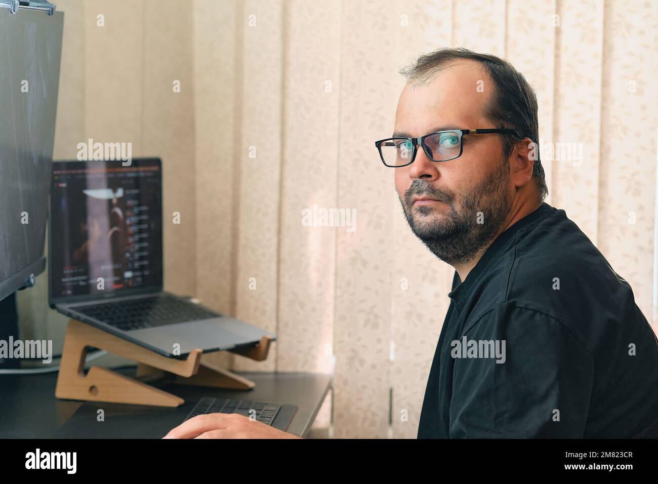 Un uomo europeo in occhiali lavora al computer Foto Stock