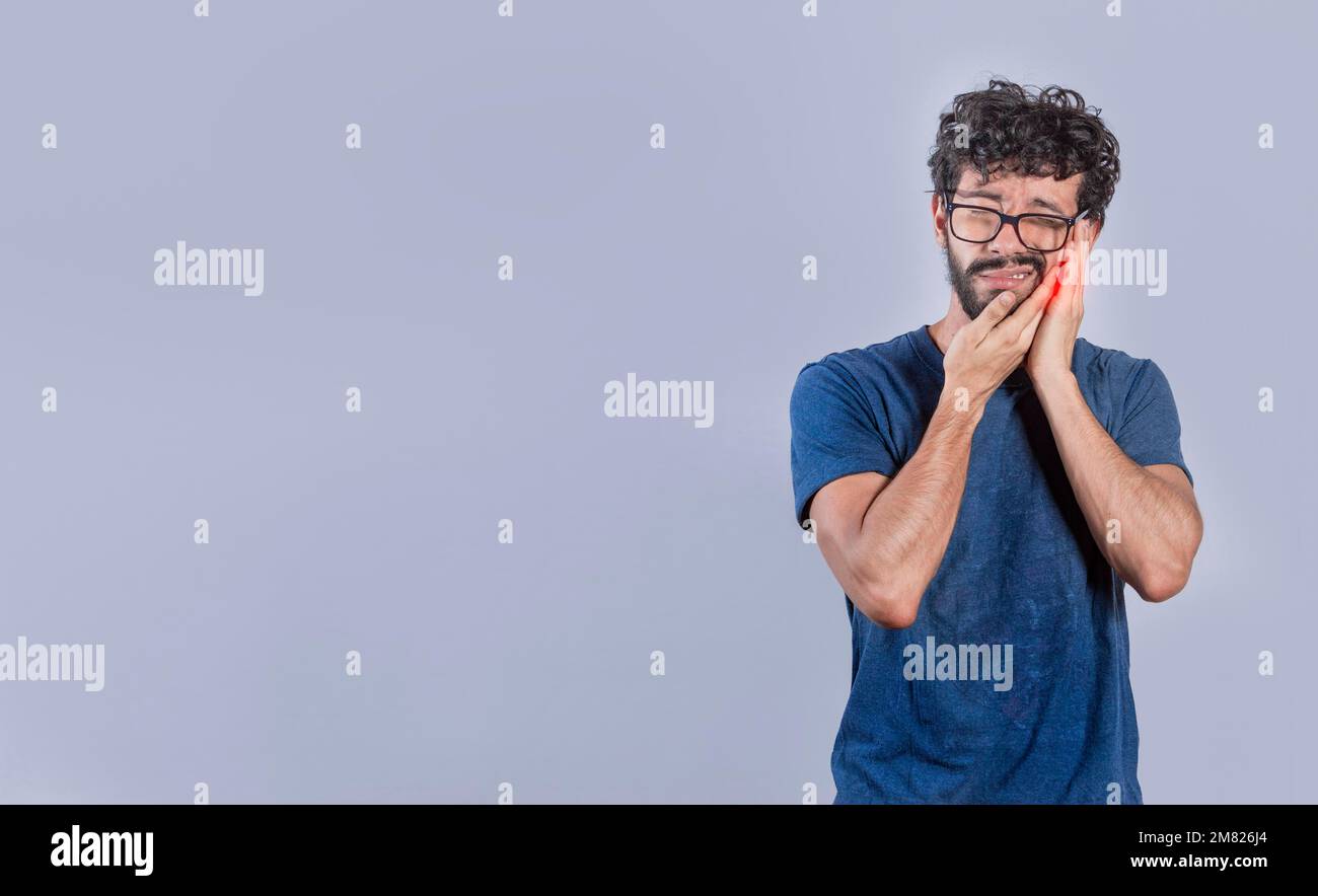 Bell'uomo con mal di denti isolato, persona con problemi di pulpite o mal di denti, concetto di persone che strofinano la guancia con mal di denti Foto Stock