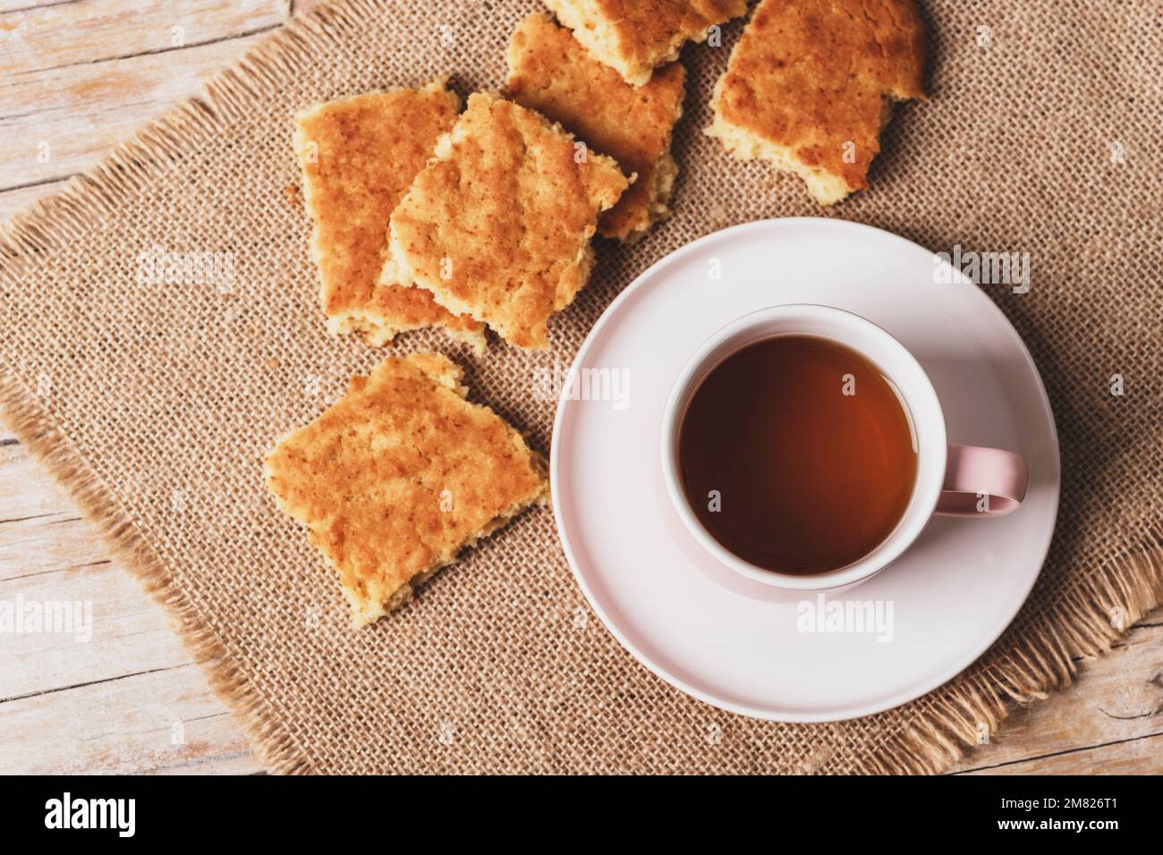 Una tazza di tè e biscotti fatti in casa su un tovagliolo di sackcloth su un tavolo di legno, vista dall'alto. Foto Stock