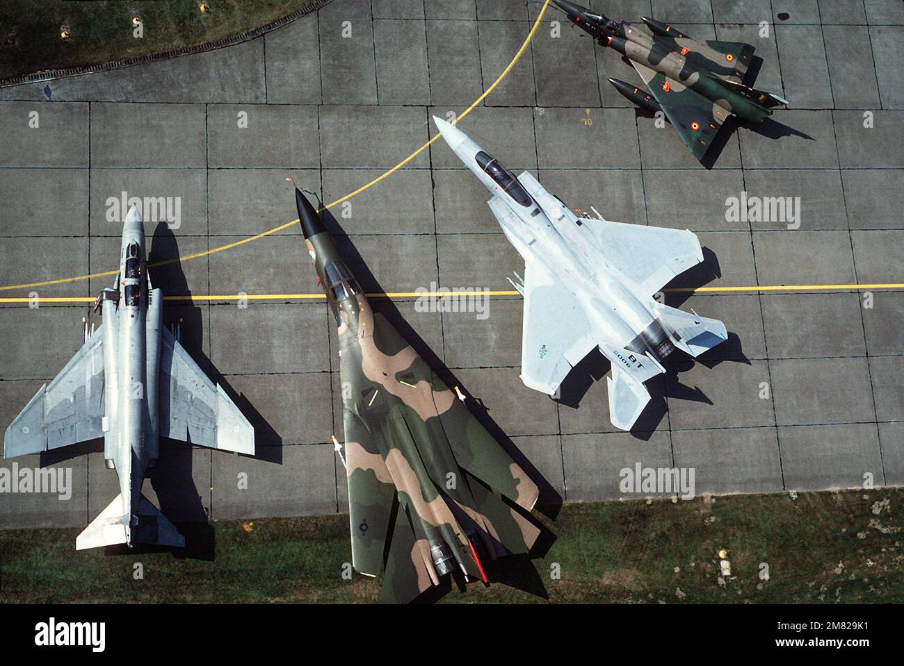 Una vista aerea di un'esposizione statica multinazionale a più velivoli che include, da sinistra a destra, un F-4 Phantom II, un F-111, un F-15 Eagle e un Mirage francese. Base: Kleine-Brogel Paese: Germania Occidentale (FRG) Foto Stock