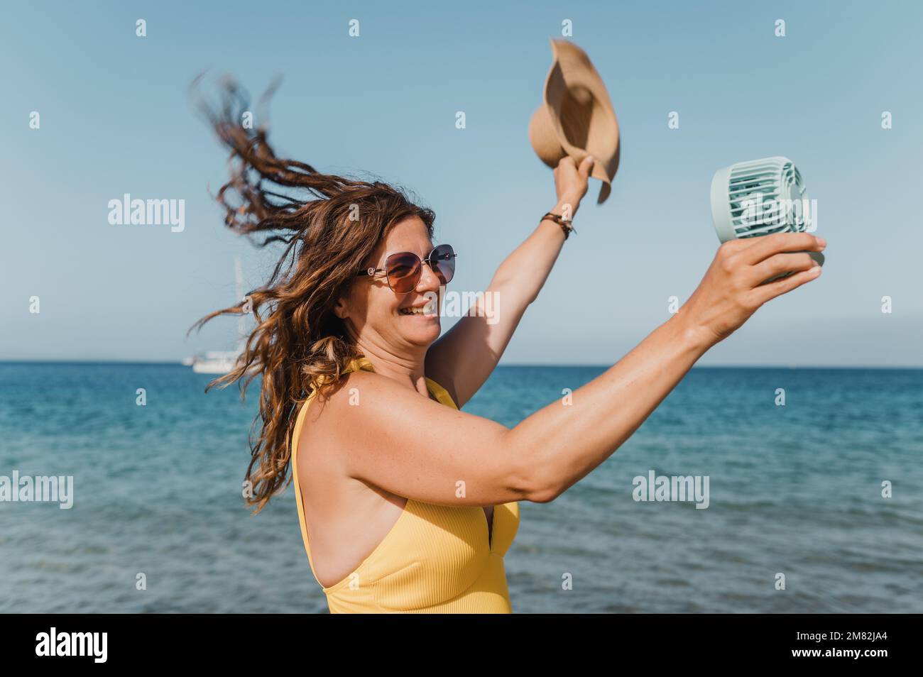 Donna allegra con ventilatore vicino al mare Foto Stock