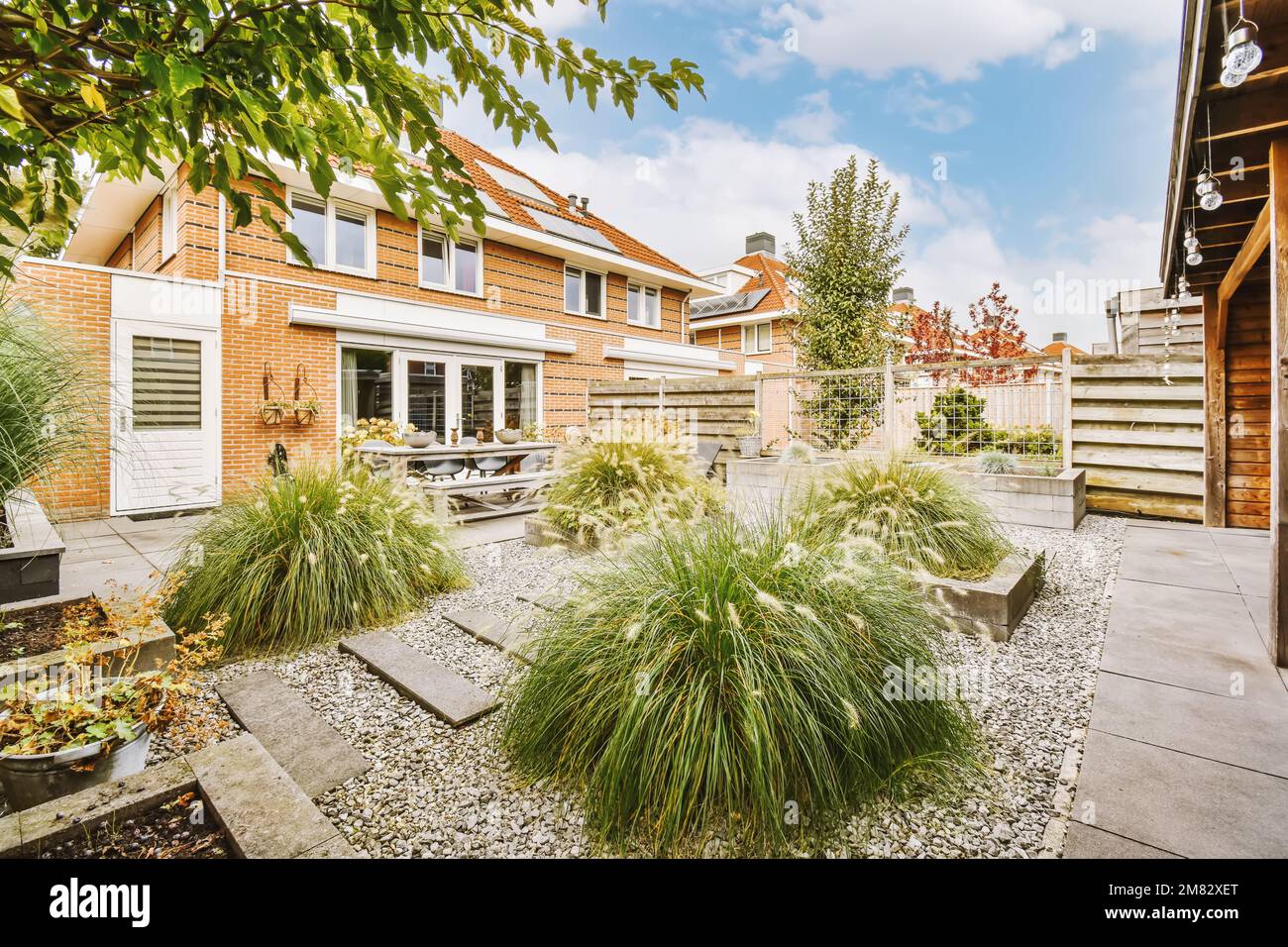 il giardino sul retro con ghiaia e piante in pentole al suolo, circondato da shutterstocker casa in mattoni rossi Foto Stock