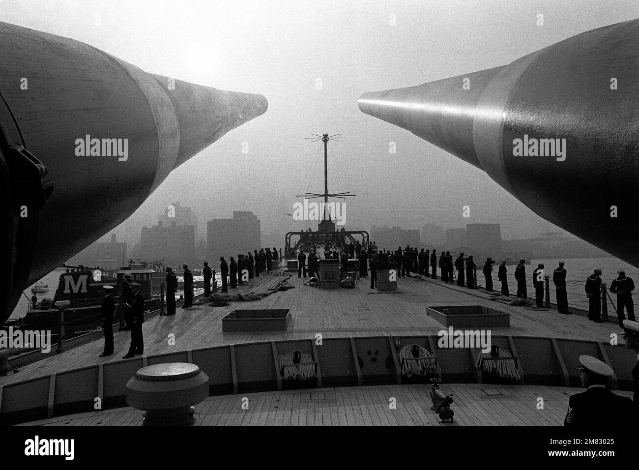 Gli equipaggi che presergono la ferrovia a bordo della nave da guerra USS IOWA (BB-61) sono incorniciati dai barili di due cannoni anteriori del calibro di Mark 7 16 pollici/50. Stato: New York (NY) Paese: Stati Uniti d'America (USA) Foto Stock