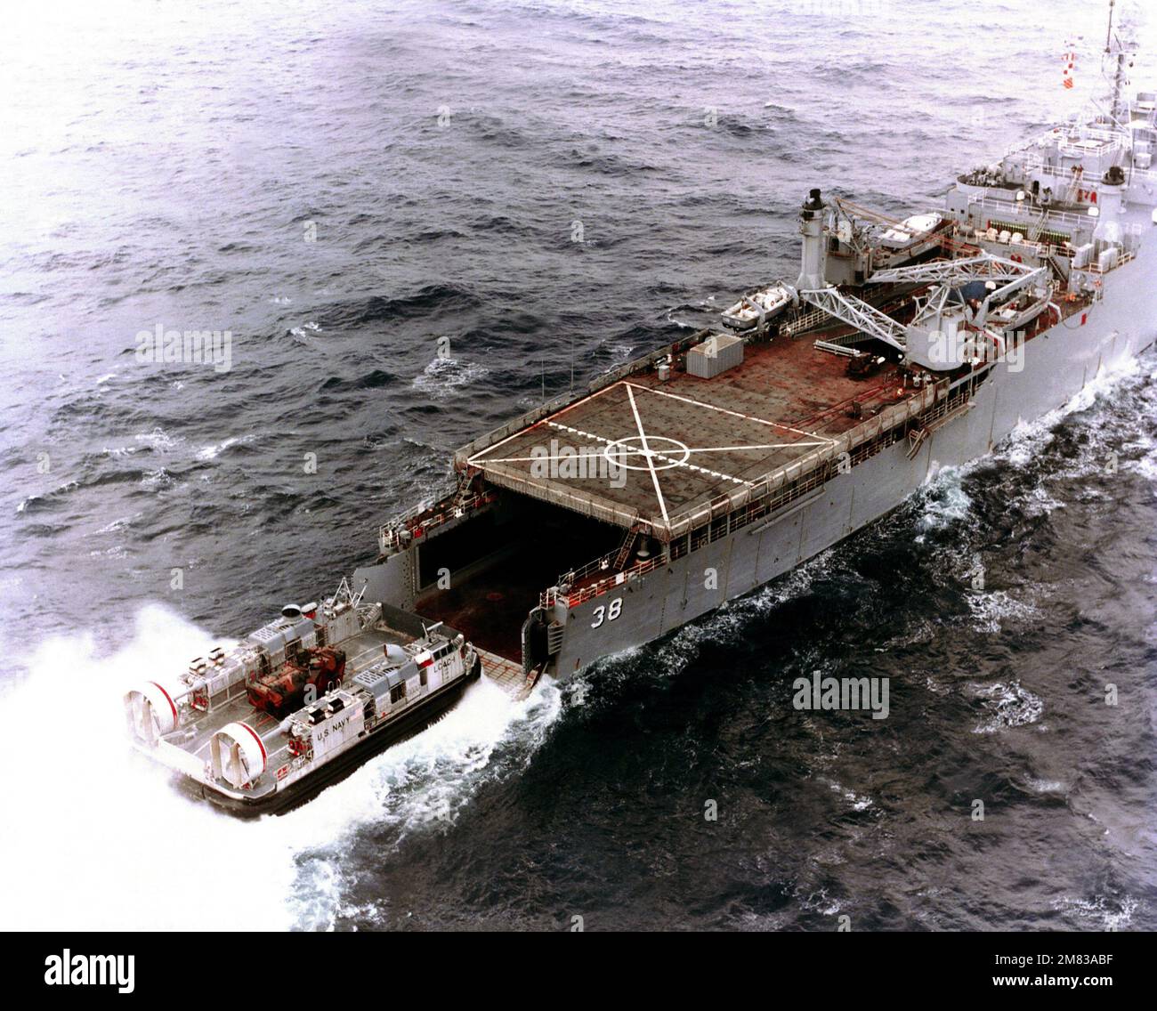 Un quarto a dritta elevato di un'imbarcazione da atterraggio a cuscino d'aria (LCAC 001) che entra nel ponte pozzi della nave da sbarco USS PENSACOLA (LSD 38) durante il primo accoppiamento in corso tra una LCAC e una LSD. L'LCAC sta trasportando un veicolo di atterraggio per il personale cingolato LVTP 7. Nazione: Golfo del Messico Foto Stock