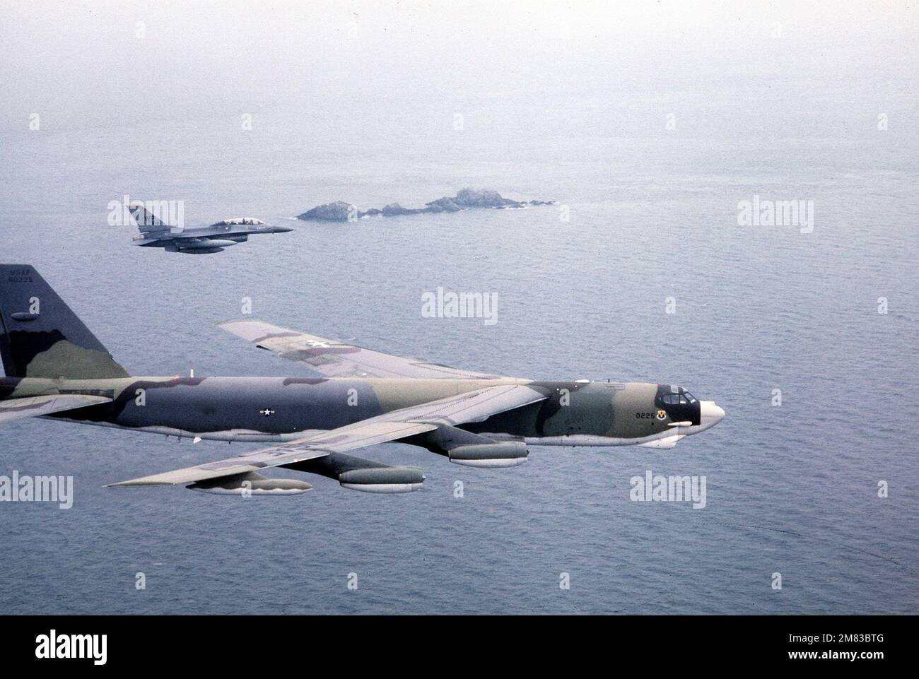 Un aereo tattico Fighter Wing F-16B Fighting Falcon del 8th accompagna un aereo strategico Wing B-52G Stratofortress del 43rd in una missione mineraria aerea sul porto di Yosu durante l'esercizio Team Spirit '85. Soggetto operativo/Serie: TEAM SPIRIT '85 base: Yosu Harbor Paese: Corea del Sud Foto Stock