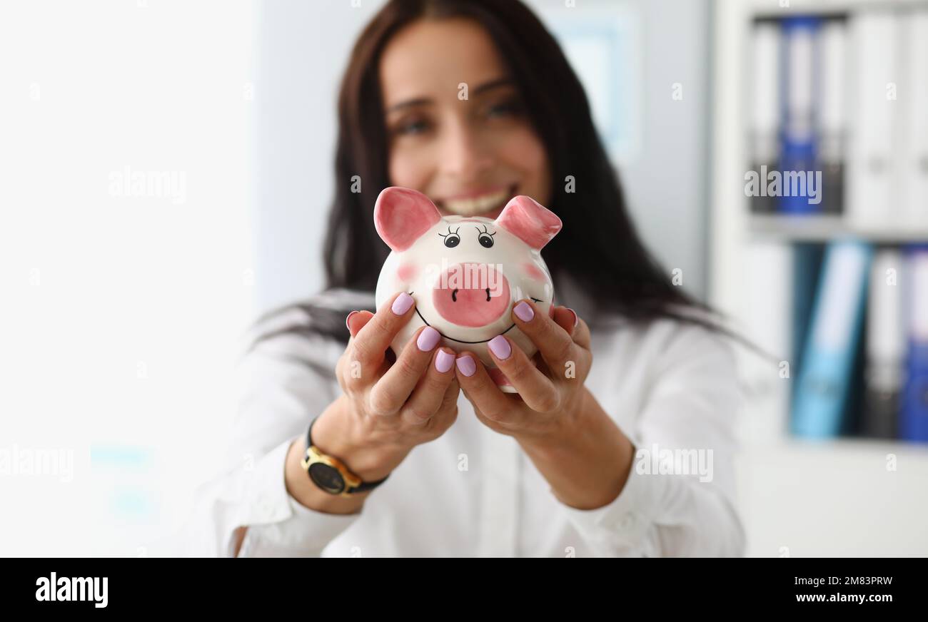 Donna d'affari sorridente che tiene bianco rosa piggy banca Foto Stock