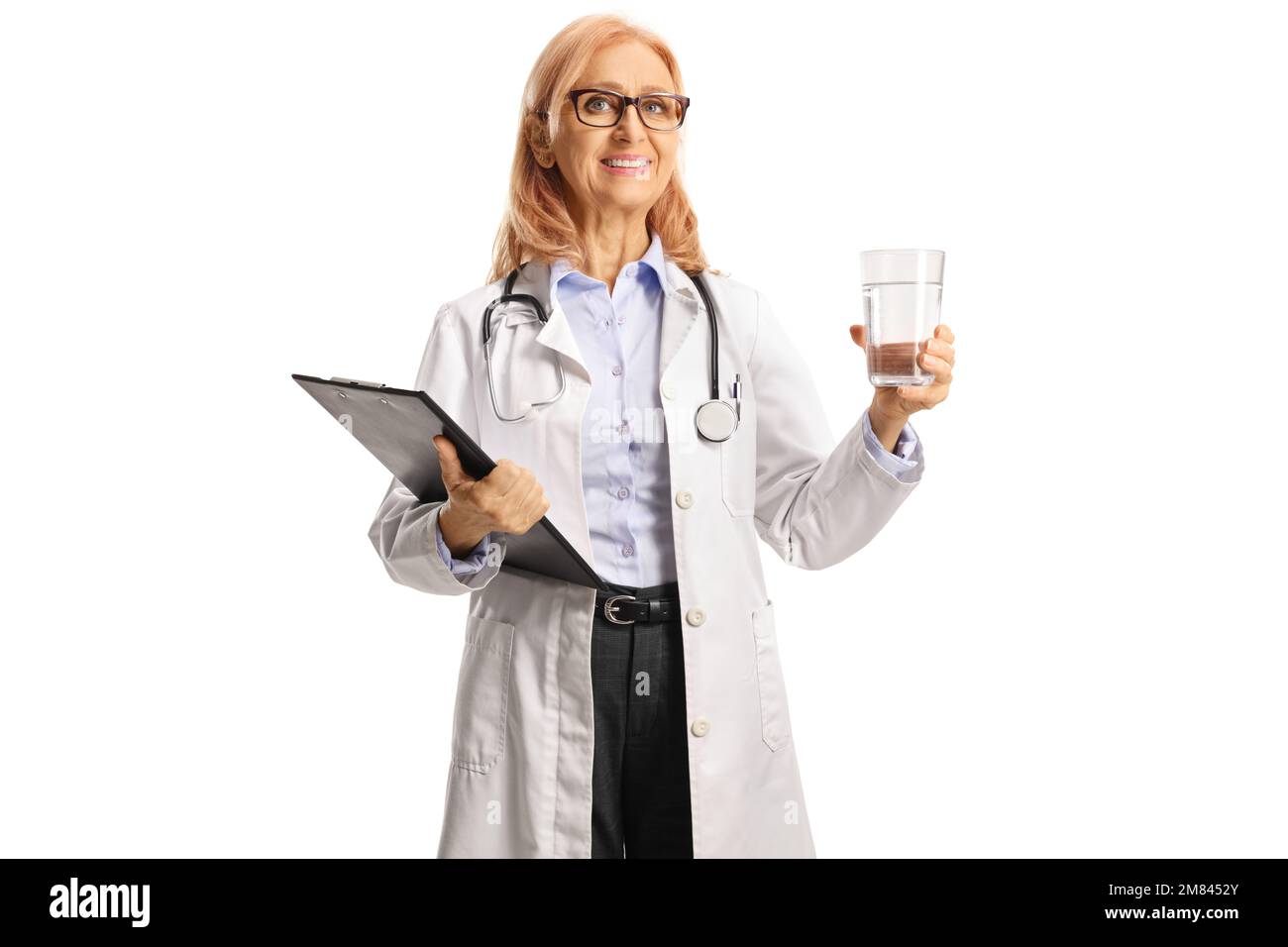 Medico femminile che tiene un bicchiere d'acqua e sorridente isolato su sfondo bianco Foto Stock