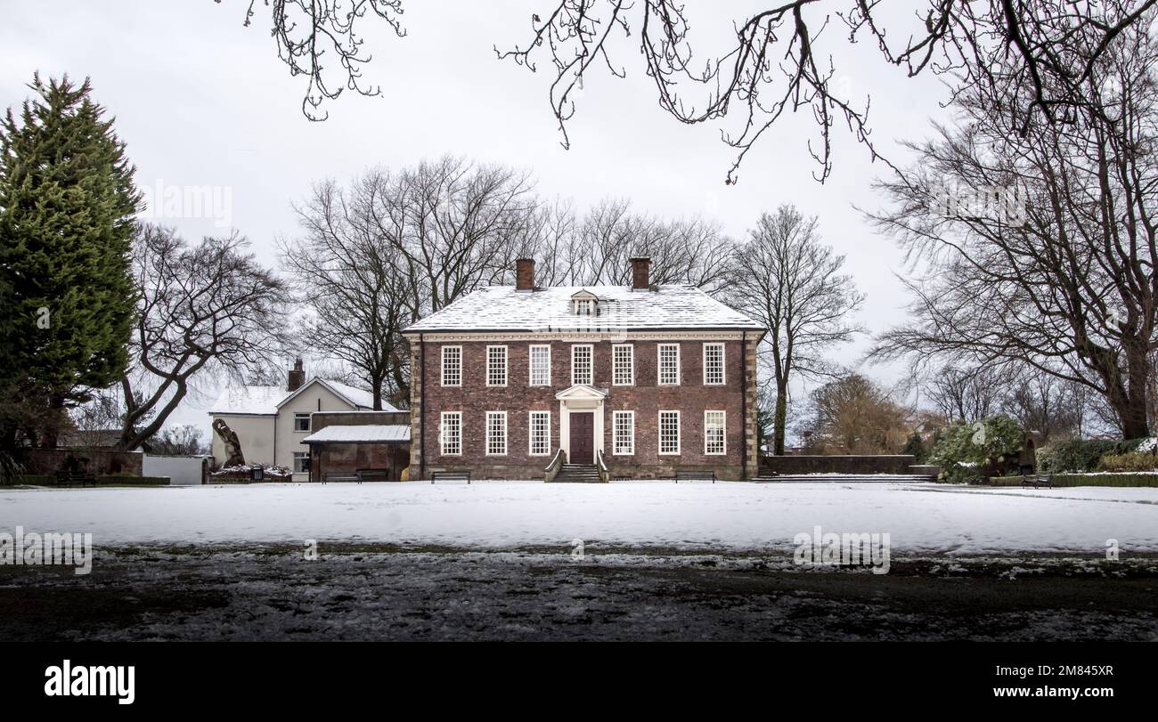 Un edificio in mattoni a due piani in inverno con alberi coperti di neve Foto Stock