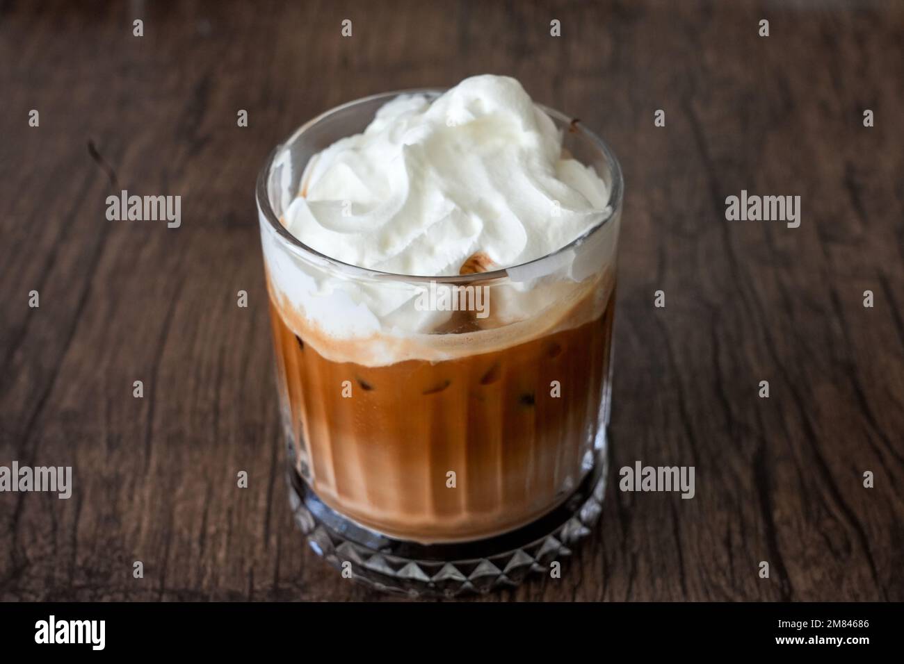 Bicchiere con moka di ghiaccio con panna montata. Bevanda fredda a base di caffè su sfondo marrone. Foto Stock