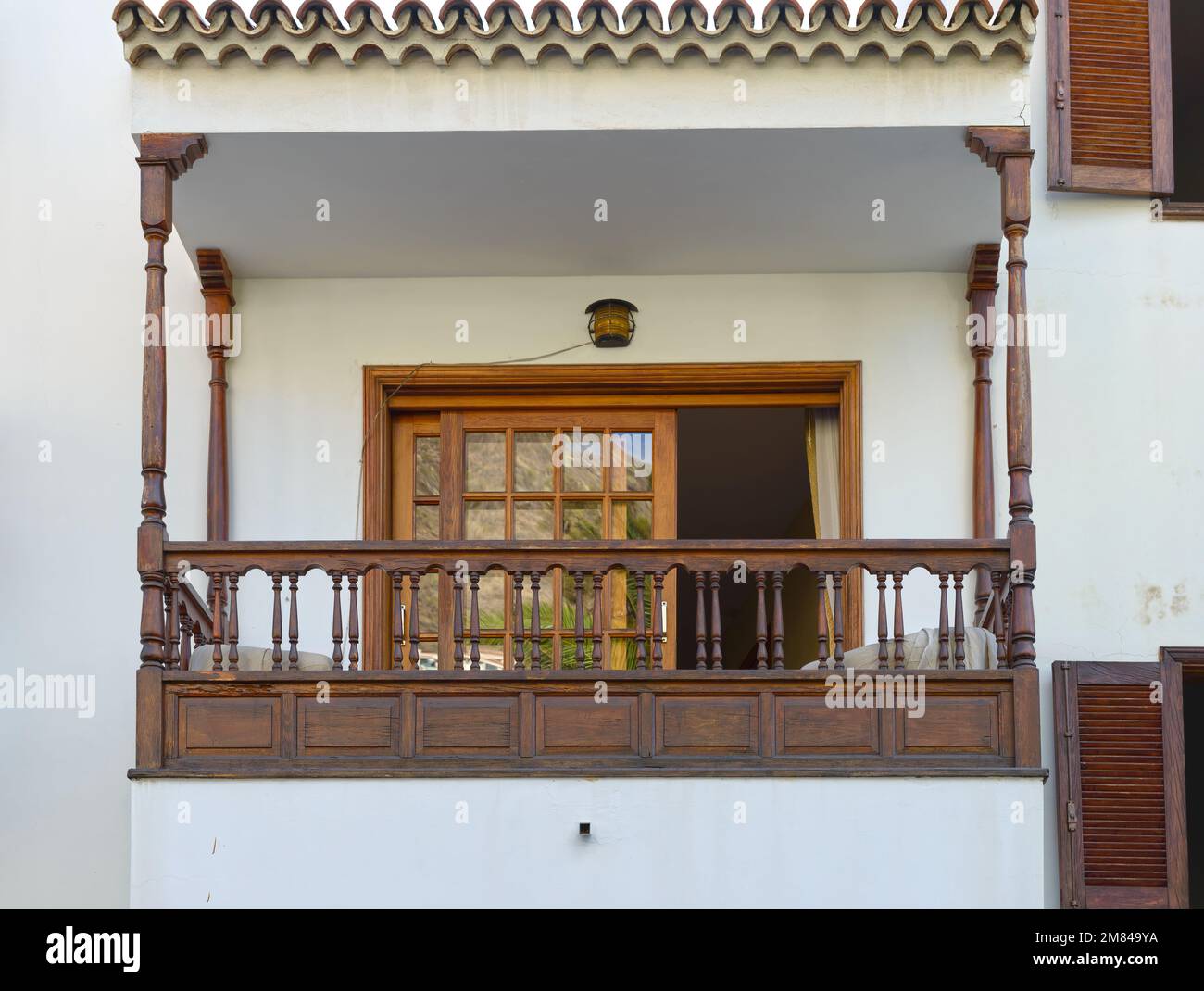 Chiusura del balcone con baldacchino in legno, ringhiera e tenda parasole orizzontale su persiane di porte e finestre. Foto Stock