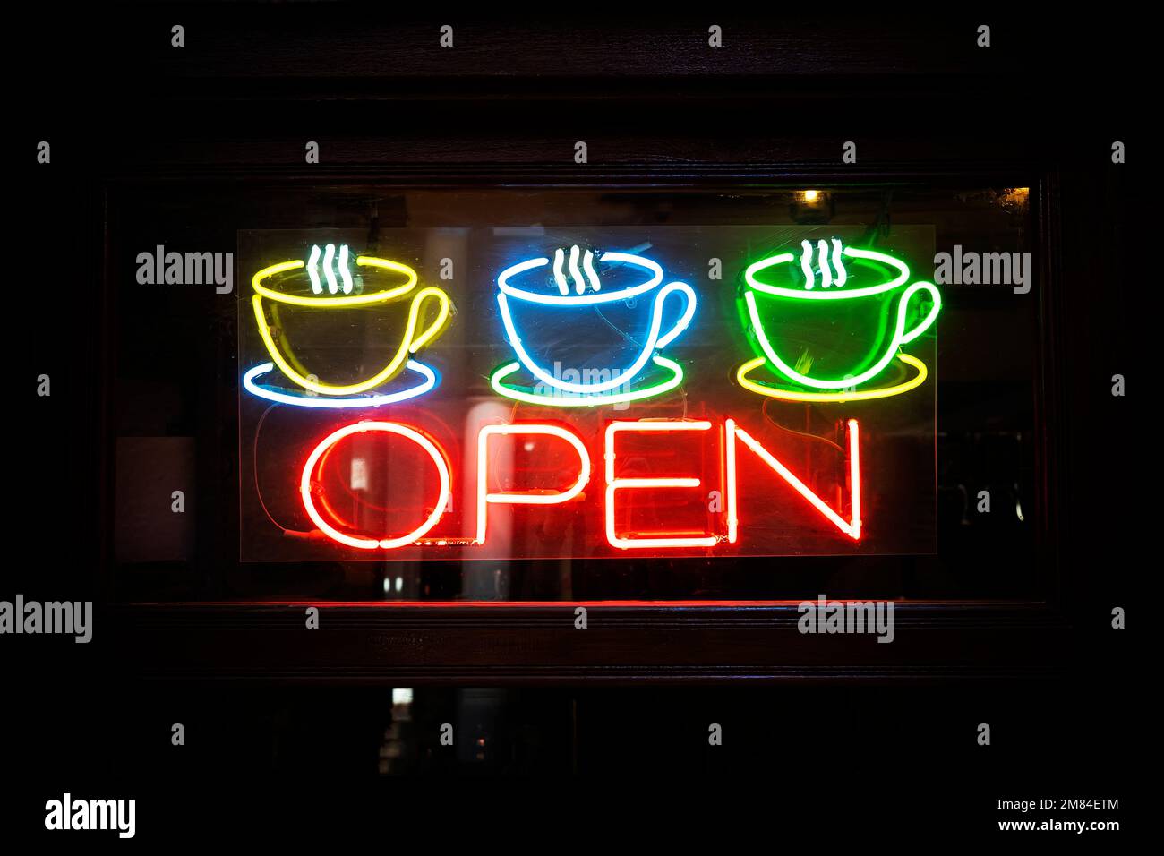 Insegna di apertura al neon con tazzina da caffè sullo sportello in vetro. una caffetteria aperta. Foto Stock