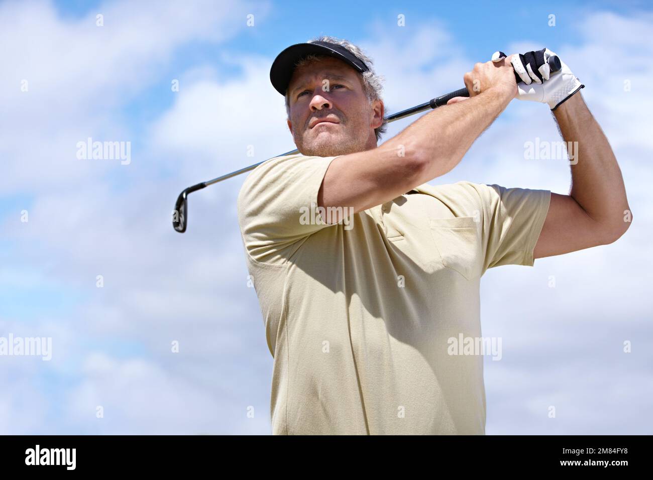 Mantieni la destra. Basso angolo sparato di un giocatore di golf maturo nella sua oscillazione posteriore. Foto Stock