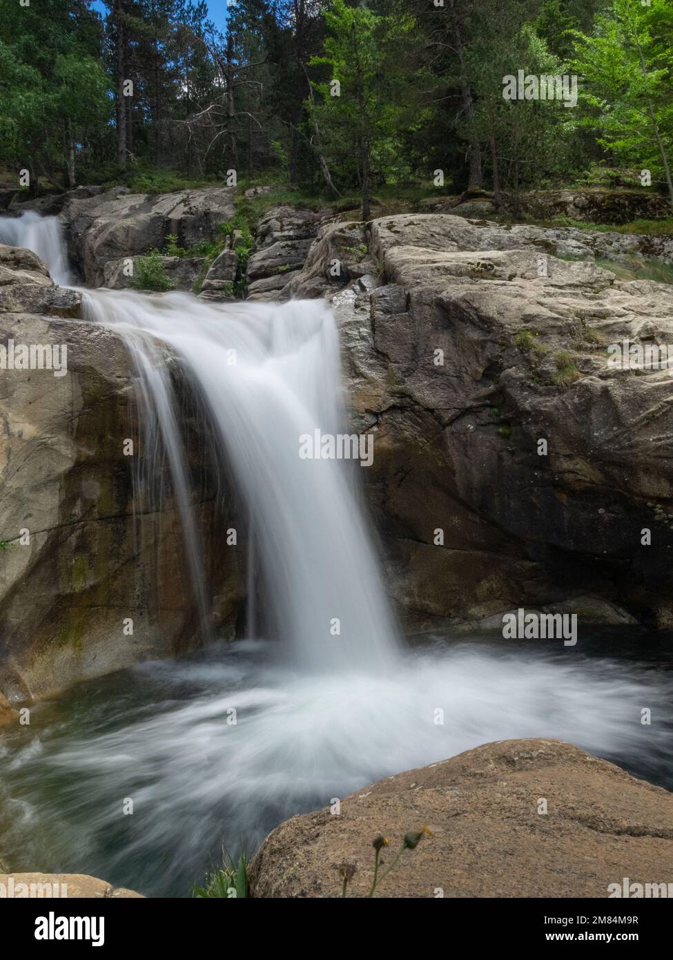 Una lunga esposizione di una cascata nella foresta verde dei Pirenei catalani Spagna in una giornata di sole Foto Stock