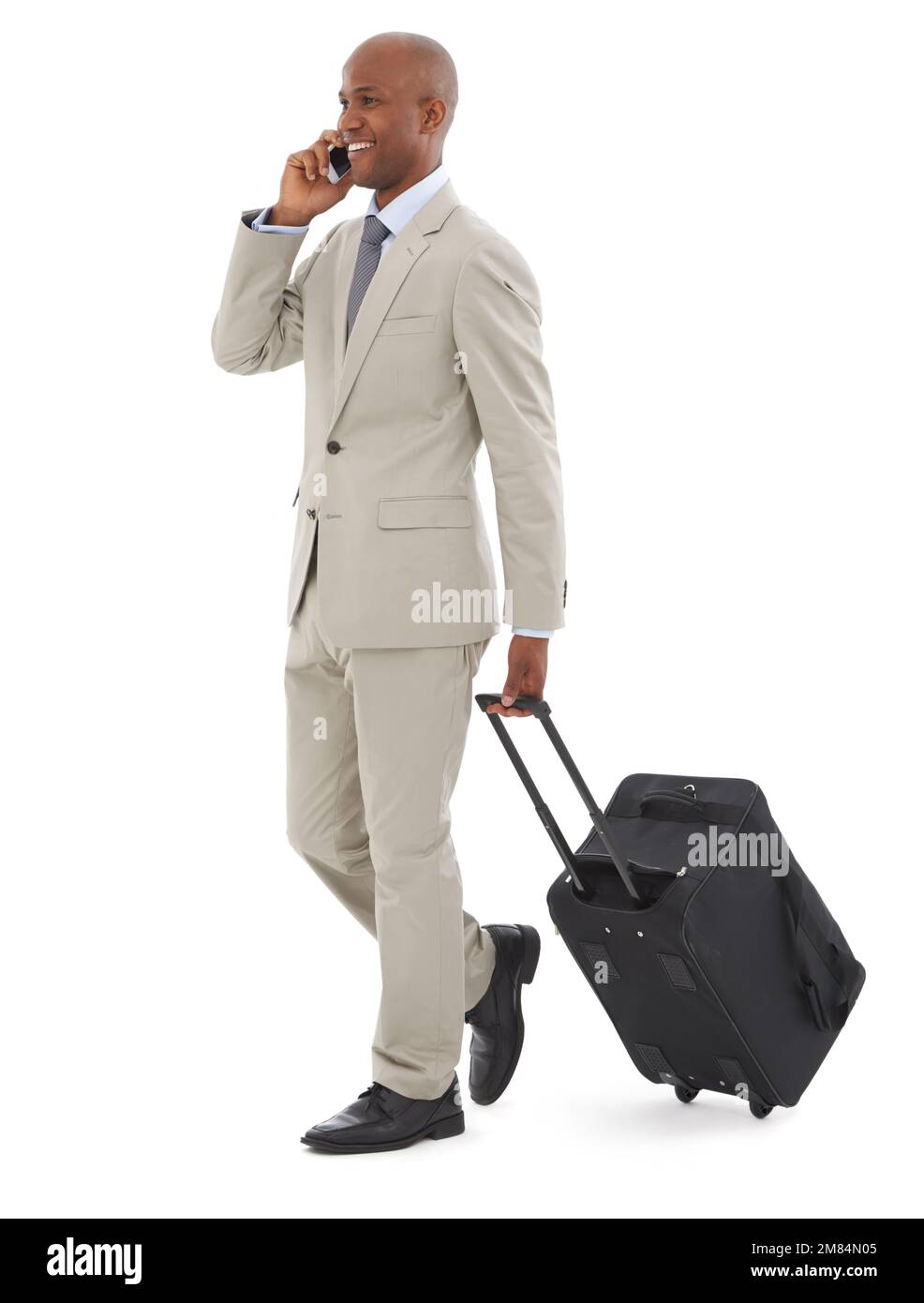 Viaggio di lavoro. Un giovane uomo d'affari afro-americano che parla al telefono mentre cammina con i bagagli. Foto Stock