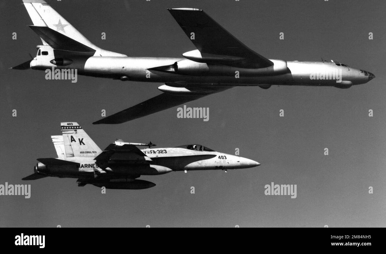 Una vista dal lato destro aria-aria di un velivolo sovietico tu-16 Badger scortato da un velivolo F/A-18A Hornet del Marine Fighter Attack Squadron 323 (VFMA-323). Paese: Sconosciuto Foto Stock