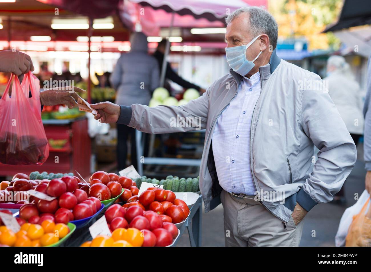 Uomo di mezza età in maschera di acquisto di verdure Foto Stock