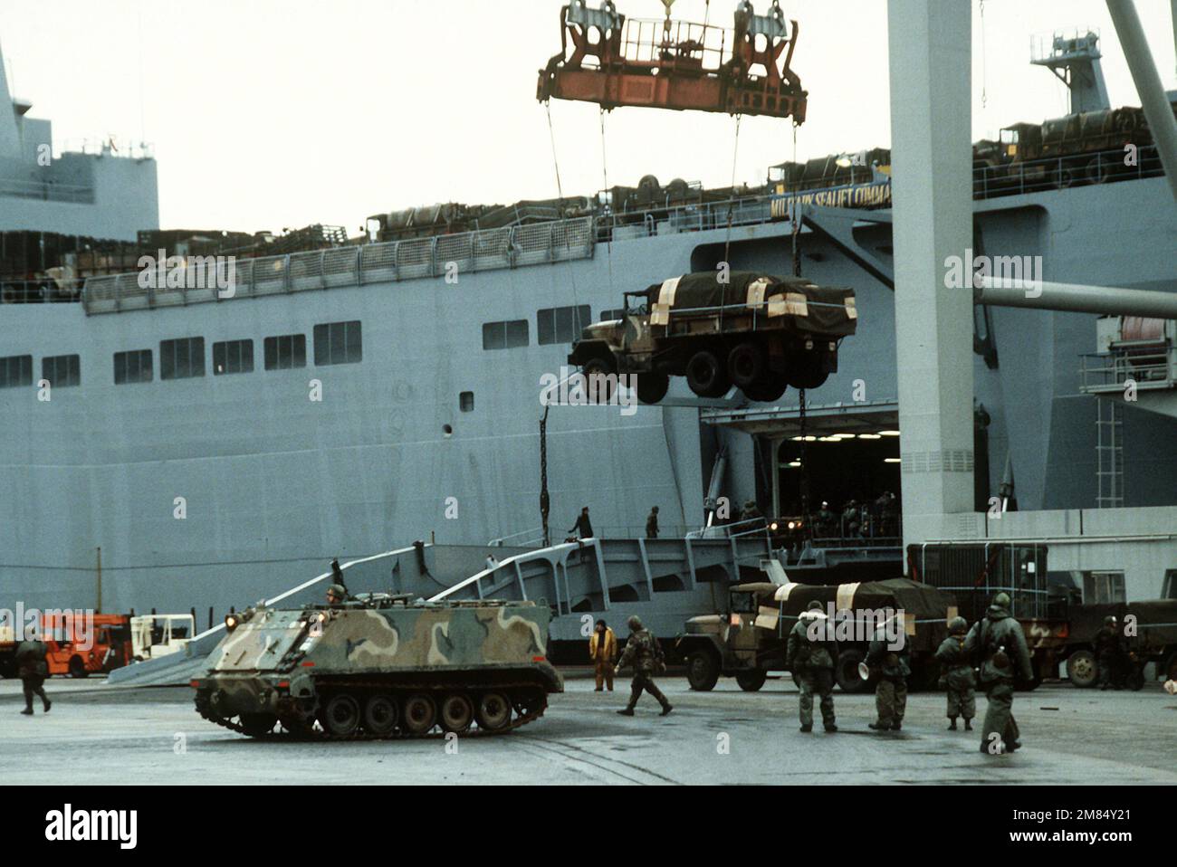 Una gru viene utilizzata per scaricare un autocarro da carico M-35A2 da 2 1/2 tonnellate dalla nave da carico/a risposta rapida USNS ANTARES (T-AKR-294) presso il Dundalk Marine Terminal. Il camion è stato utilizzato dalla 32nd separata Brigata della Fanteria (meccanizzata), Wisconsin Army National Guard, durante l'esercizio Reforger '86. Una carrier del personale blindato M-113 è parcheggiata sul molo. Base: Baltimore Stato: Maryland (MD) Paese: Stati Uniti d'America (USA) Foto Stock