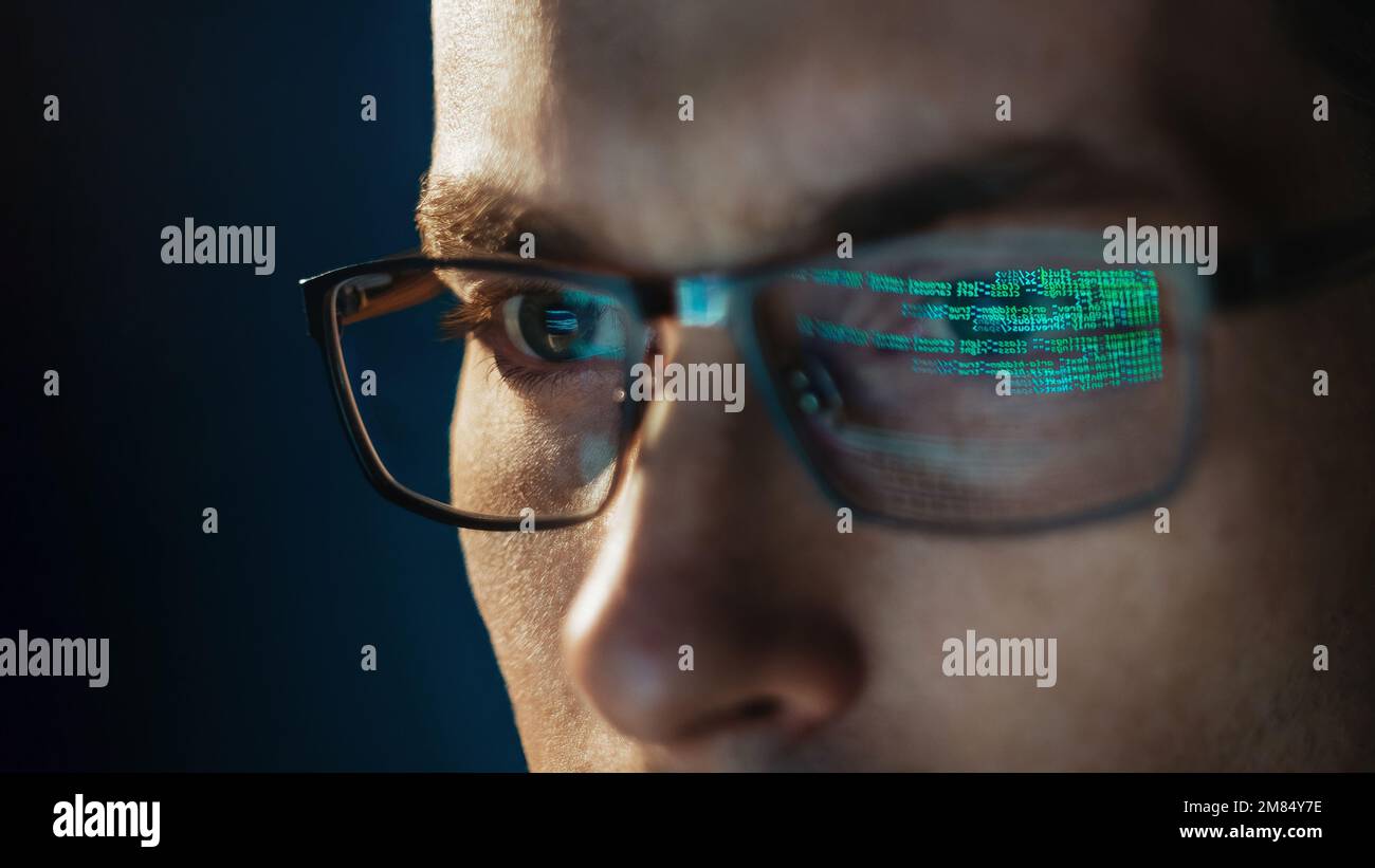 Primo piano ritratto di un ingegnere software messo a fuoco indossando occhiali guardando lo schermo del computer lavorando con i big data. Codice di programmazione che si riflette negli occhiali. Scienza dei dati, apprendimento automatico, concetto di intelligenza artificiale Foto Stock