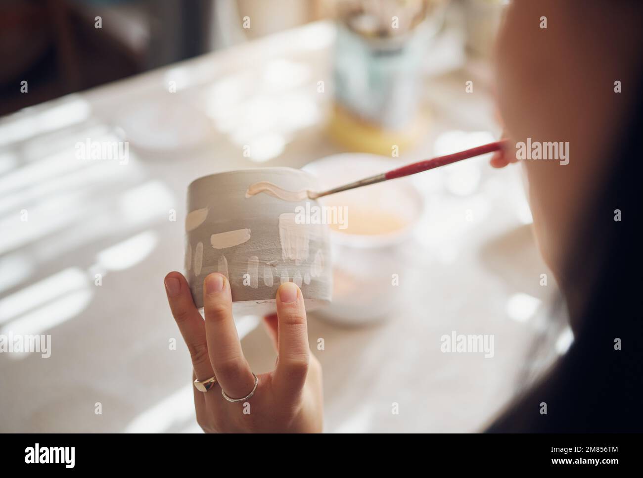Mani da donna, studio di ceramica e coppa di pittura in officina per scultura, produzione creativa o design. Pittore, prodotto ceramico e processo a pennello Foto Stock