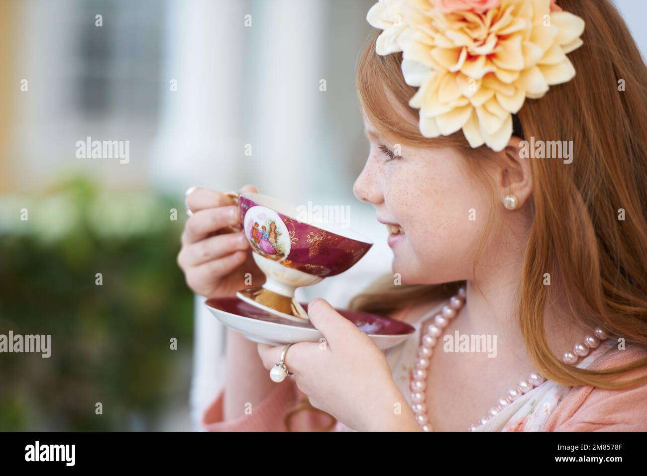 OH, mi piace il tè. Una bambina che gioca vestire e avere una festa del tè nel suo giardino. Foto Stock