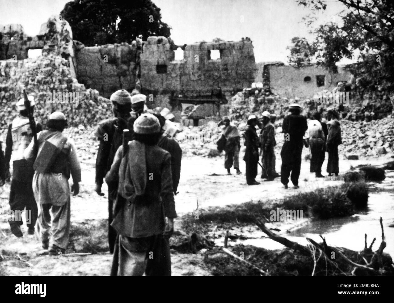 I combattenti della resistenza afghani ritornano in un villaggio distrutto dalle forze sovietiche. Paese: Afghanistan (AFG) Foto Stock