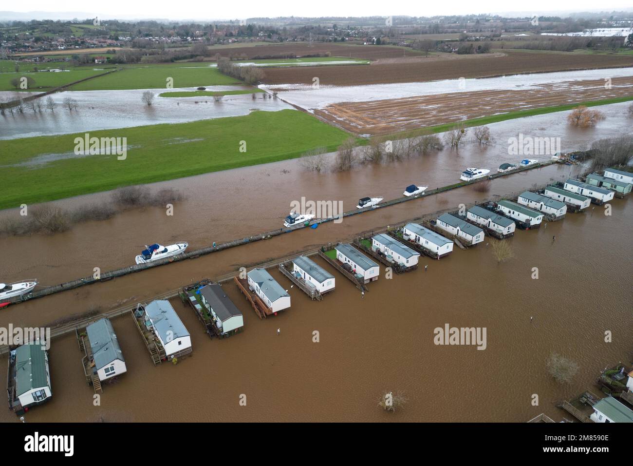 Kempsey, Worcestershire, 12 gennaio 2023 - le carovane natalizie presso il campo ricreativo di Seaborne a Kempsey, Worcestershire sono state abbandonate dall'acqua alluvionale dopo che il fiume Severn ha fatto esplodere le sue sponde. Le carovane statiche rialzate hanno ora la vista di un grande specchio d'acqua e di imbarcazioni da diporto ormeggiate fuori portata. Si prevede che il livello del fiume raggiunga il picco il sabato. Credito: Interrompi stampa Media/Alamy Live News Foto Stock