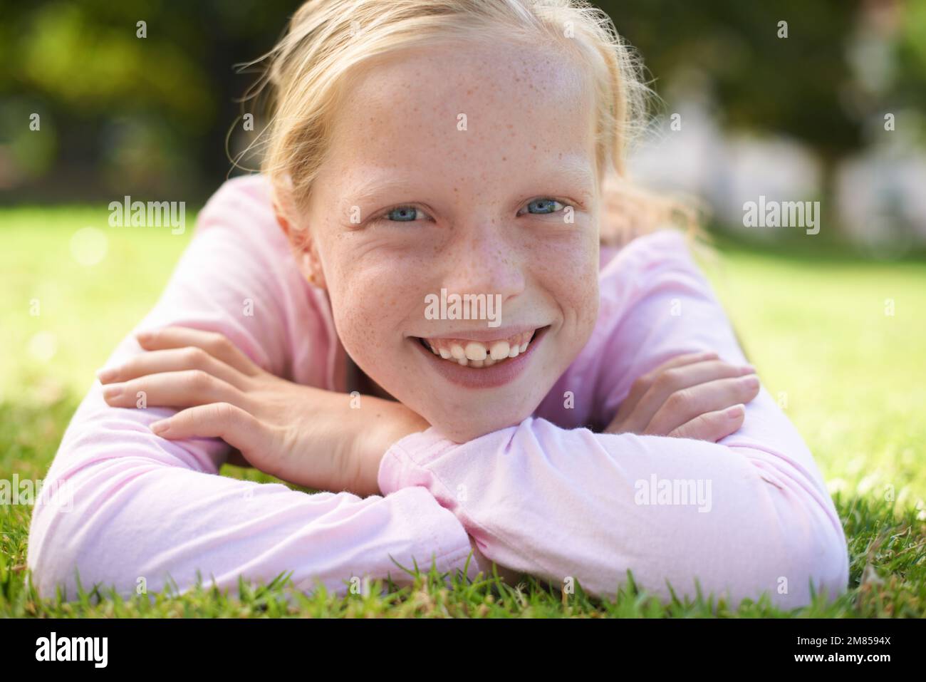 Godersi un'estate soleggiata. Ritratto di una giovane ragazza sdraiata sull'erba fuori. Foto Stock