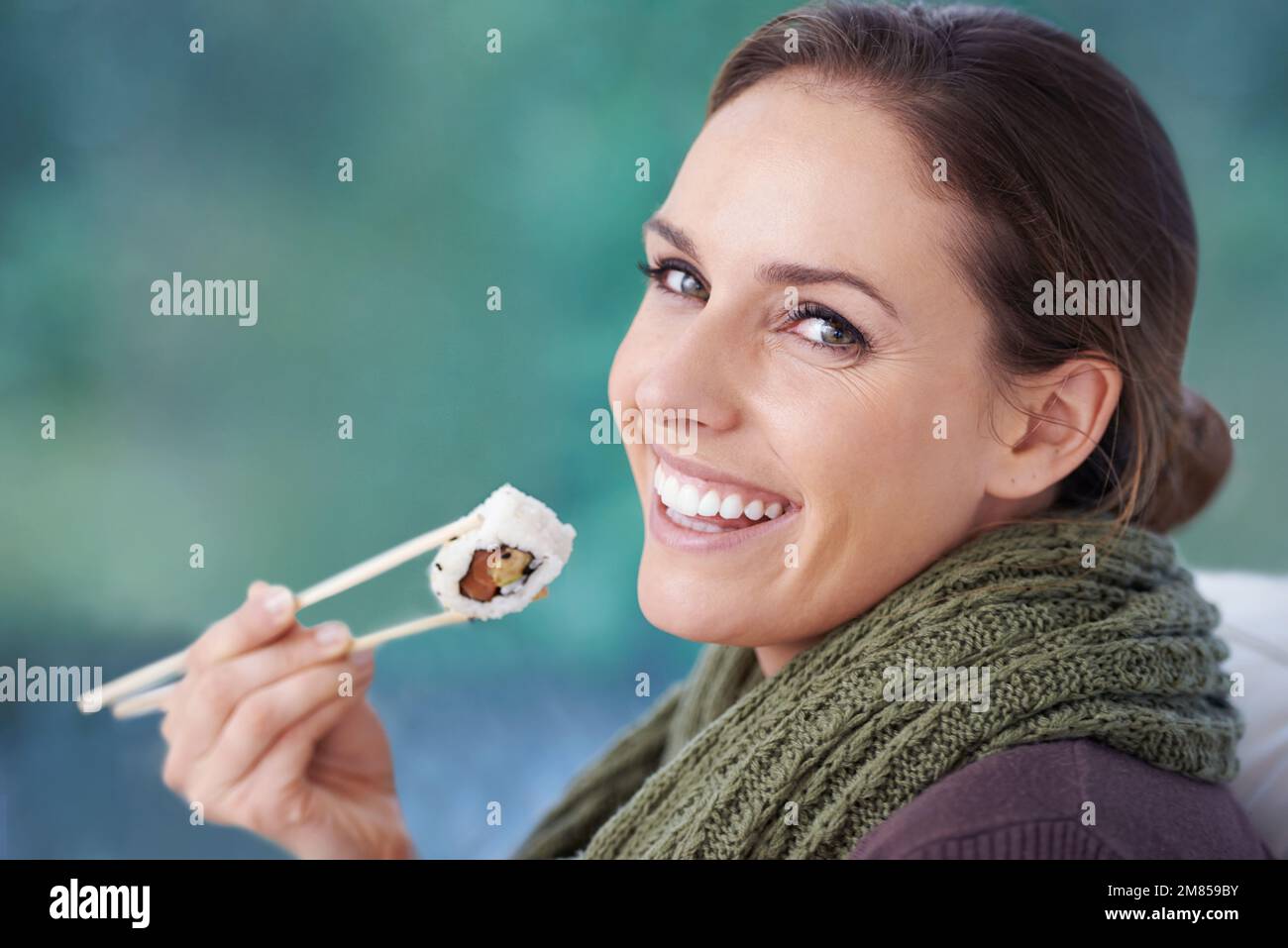 Ho un soft spot per il sushi. Una giovane donna sorridente mentre tiene un pezzo di sushi. Foto Stock