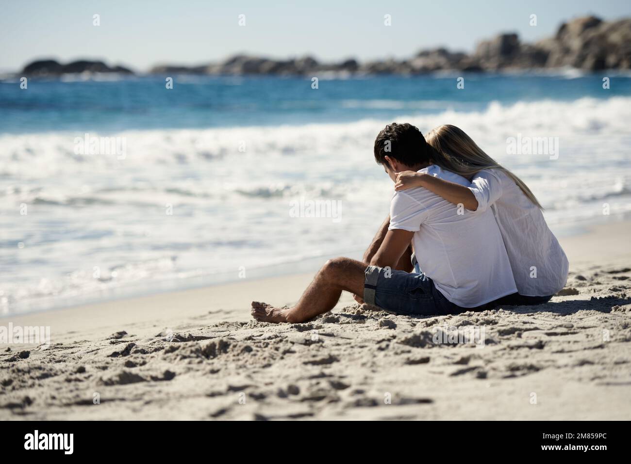 Relax con la mia speciale. Una coppia seduta sulla spiaggia che guarda all'oceano. Foto Stock