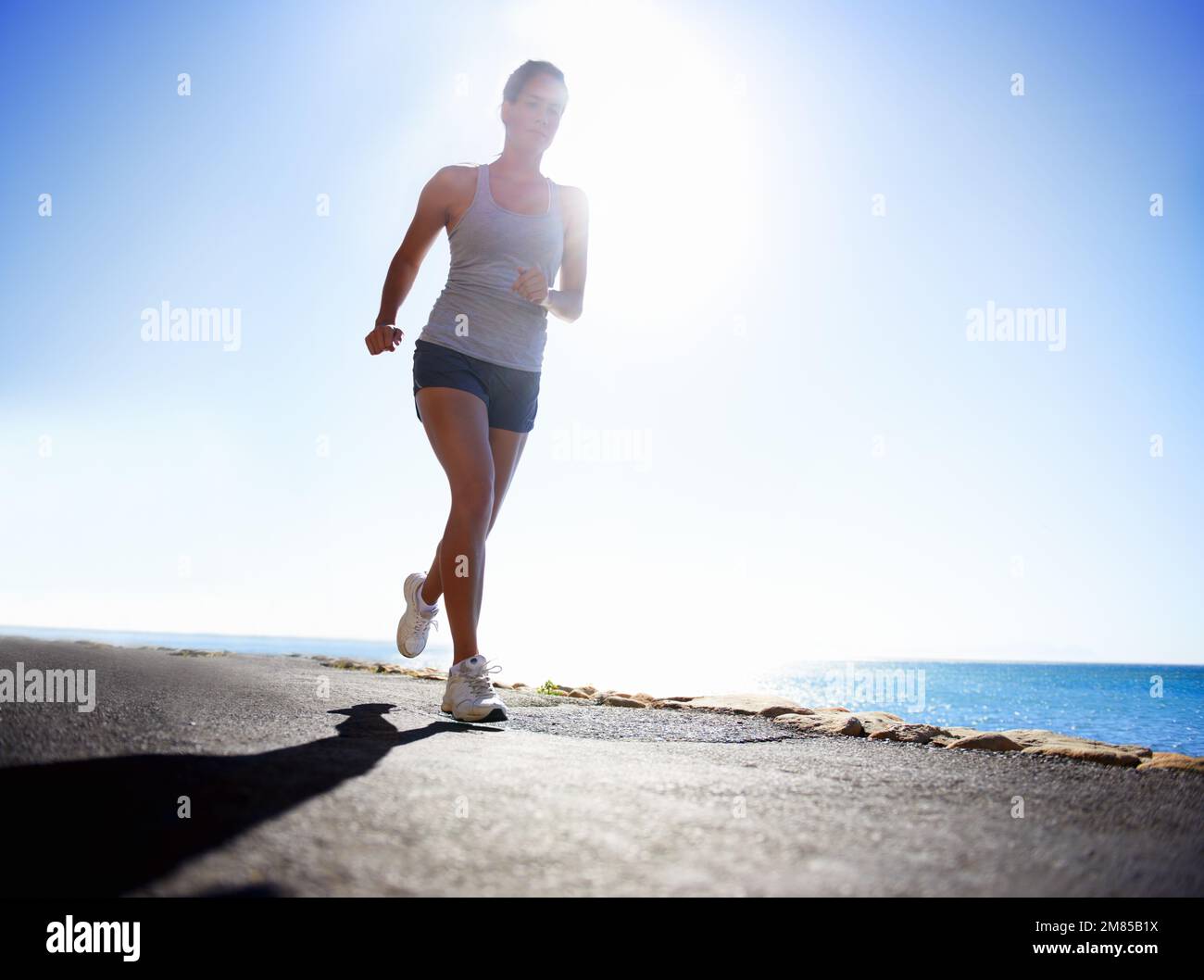 La corsa è uno stile di vita. Vista ad angolo basso di un runner vicino all'oceano. Foto Stock