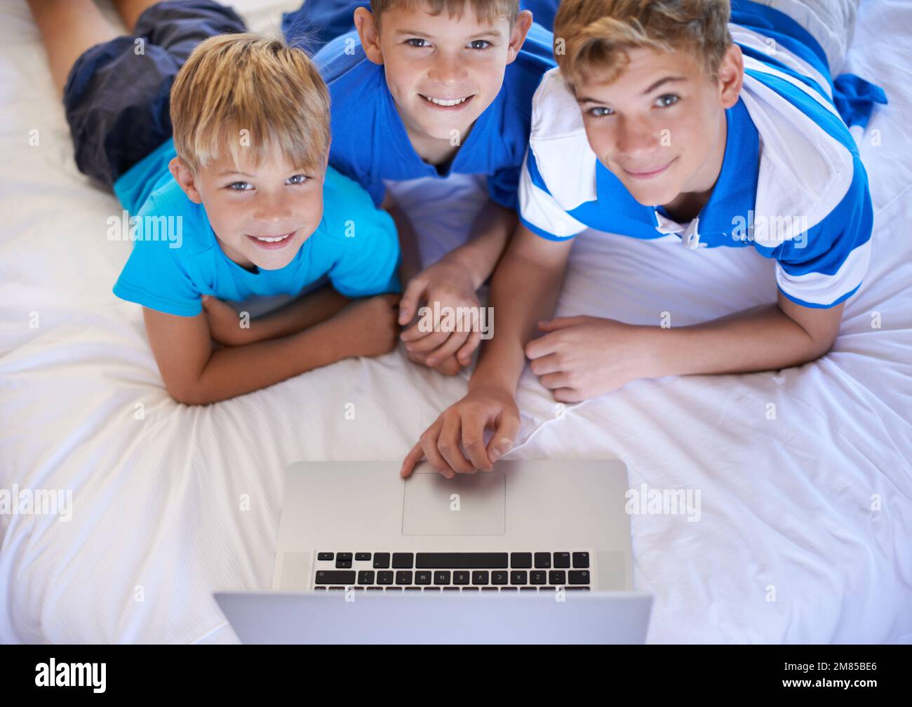 I bambini di oggi sono così esperti di tecnologia. Tre fratelli che  navigano in Internet insieme su un computer portatile Foto stock - Alamy