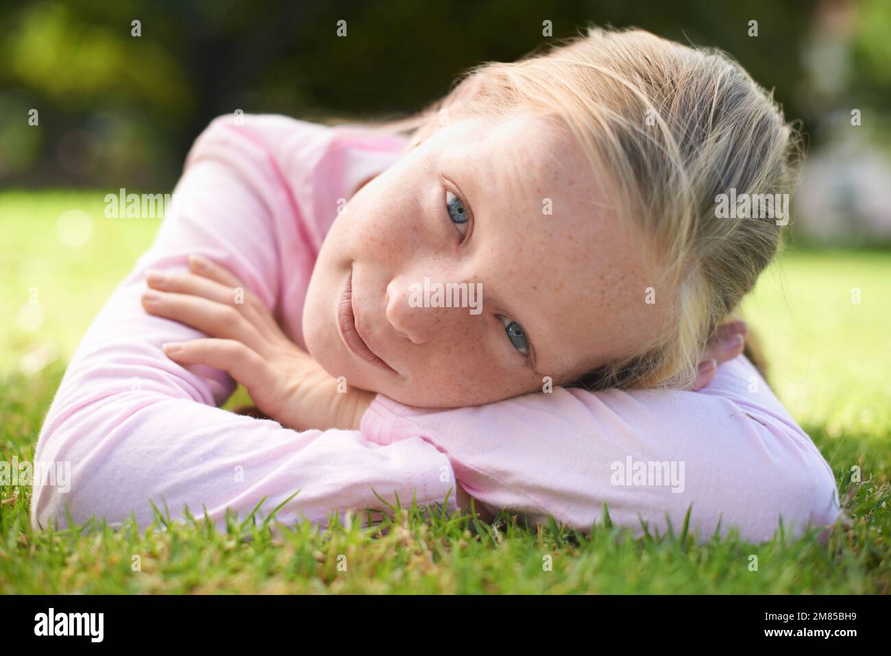 Godersi il sole estivo. Ritratto di una giovane ragazza sdraiata sull'erba fuori. Foto Stock