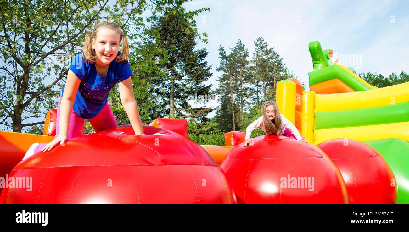 Felice bambine avente un sacco di divertimento durante il salto dal giunto a sfera su un gonfiare il castello. Foto Stock