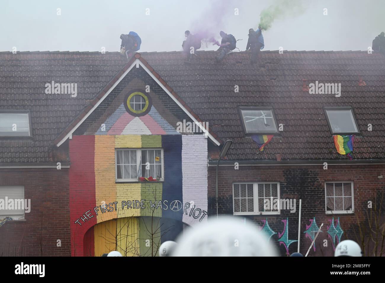 Erkelenz, Germania. 12th Jan, 2023. Gli attivisti infiammano i pirotecnici sul tetto di una casa il secondo giorno dello sfratto nella frazione lignita di Lützerath occupata dagli attivisti climatici. L'azienda energetica RWE vuole scavare il carbone che si trova sotto Lützerath - a questo scopo, il borgo sul territorio della città di Erkelenz presso l'opencast lignite miniera Garzweiler II è da demolire. Credit: Henning Kaiser/dpa/Alamy Live News Foto Stock