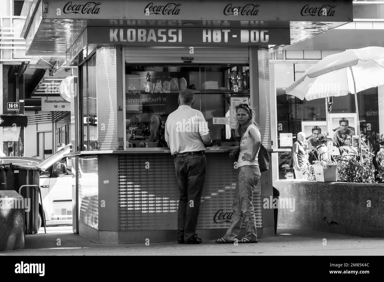 Mads Jacobsen, busker, suonando la chitarra seduto sul muro vicino allo stand hotdog sulla Rotenturmstrasse a Vienna mentre la coppia compra il pranzo Foto Stock
