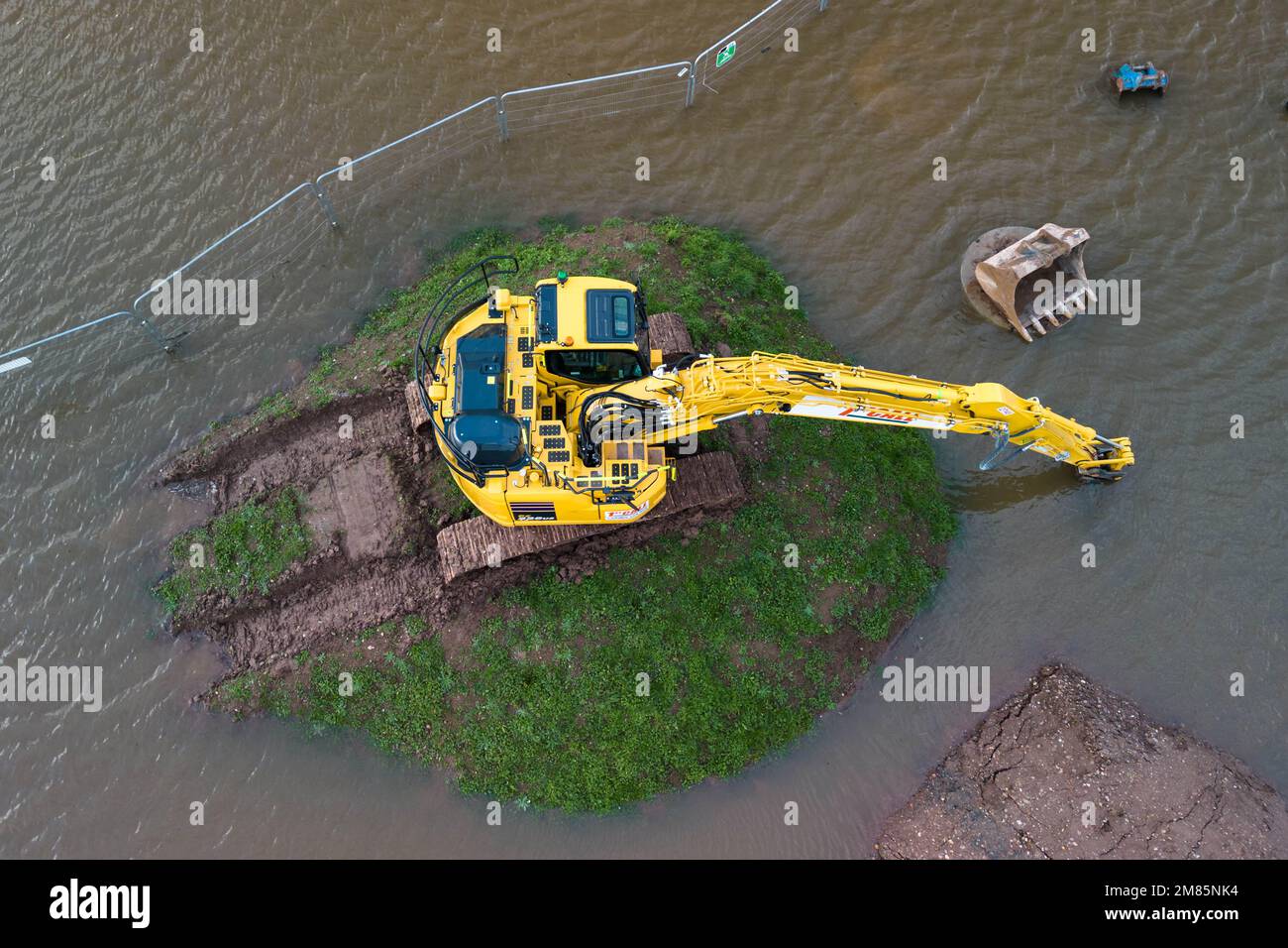 Upton-upon-Severn, Worcestershire, 12 gennaio 2023 - Una piccola città del Worcestershire è stata inondata dopo l'esplosione del fiume Severn a causa dell'innalzamento del livello dell'acqua. Un centro di riciclaggio dei rifiuti è stato chiuso insieme a una strada di accesso locale, Hanley Road, che è stata chiusa dal consiglio locale. Una grande scavatrice gialla è stata vista abbandonata su un piccolo tumulo erboso mentre l'inondazione lo circondava. Credito: Interrompi stampa Media/Alamy Live News Foto Stock