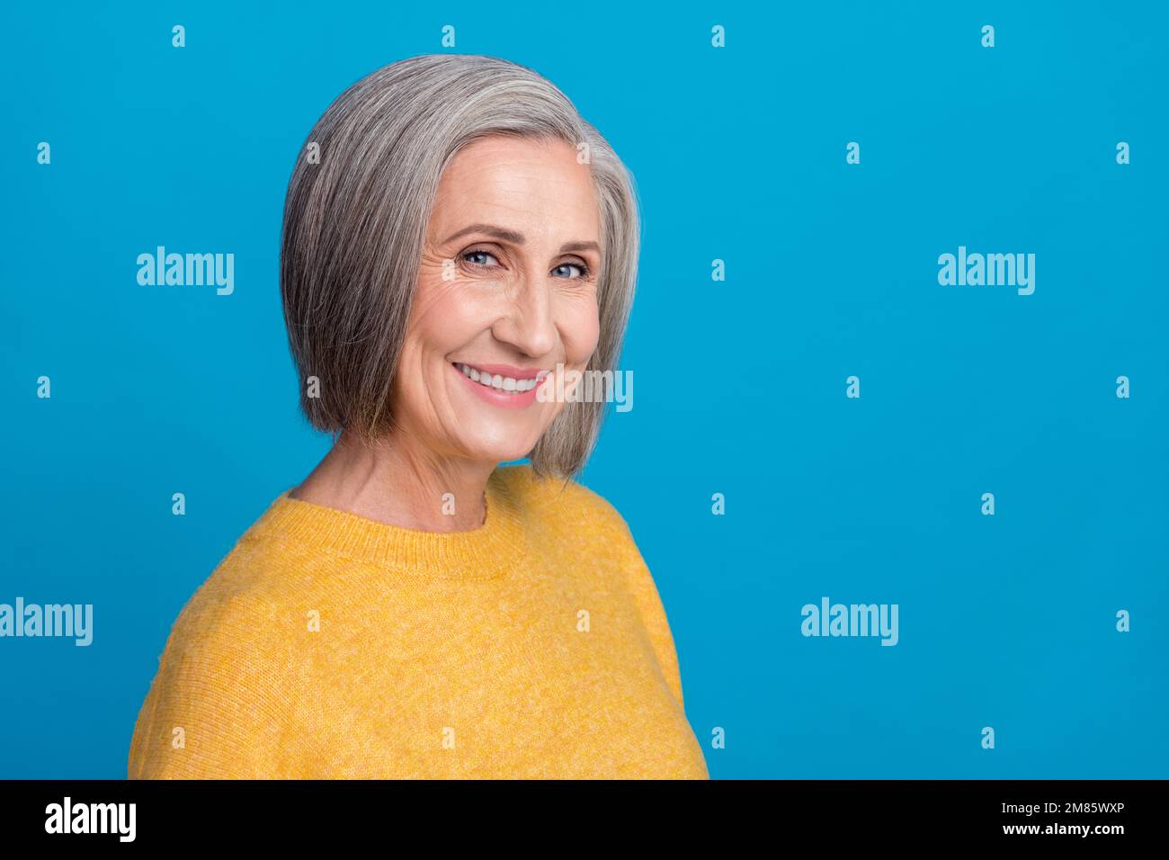 Foto ritratto di donna senior gorgeous toothy beaming sorriso cosmetologia promo indossare abiti gialli alla moda isolato su sfondo di colore blu Foto Stock