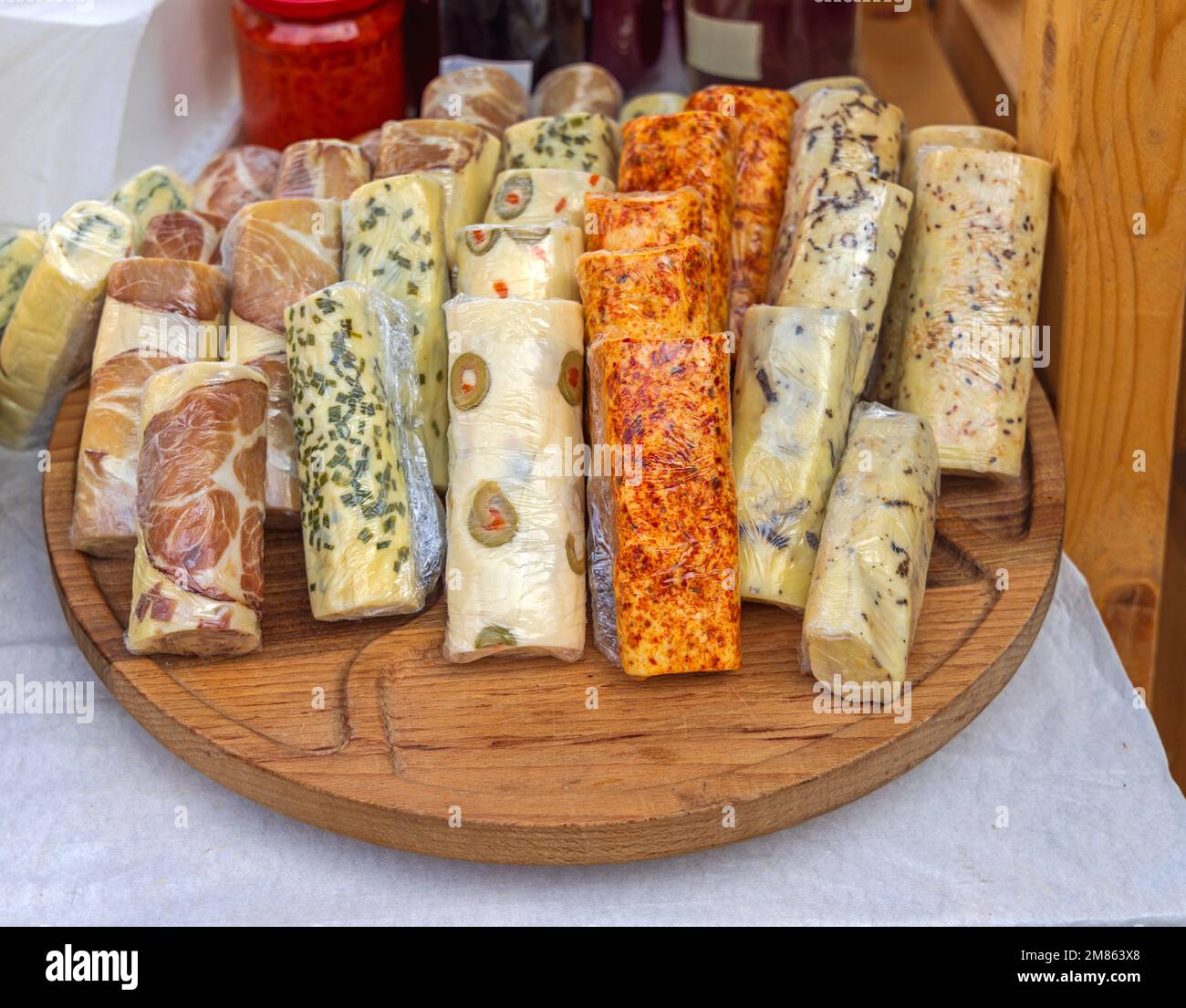 Formaggio di mucca alle erbe in forma di tronchi avvolto in pellicola di Cling Foto Stock