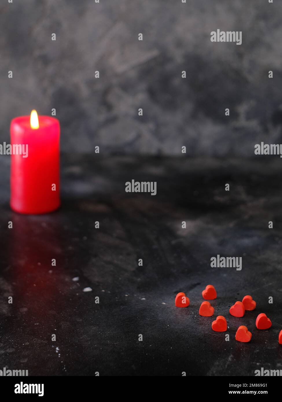Cuori rossi con candela accesa su sfondo scuro Foto Stock
