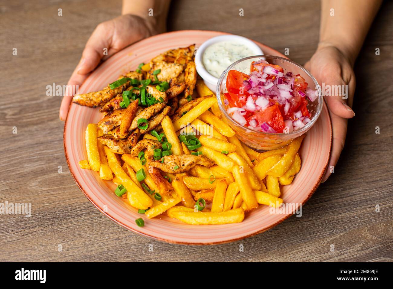 Primo piano con patatine fritte, carne, salsa e insalata di verdure isolate su fondo di tavola in legno. Servizio di piatto principale e guarnire il closeup. Arrosto Foto Stock