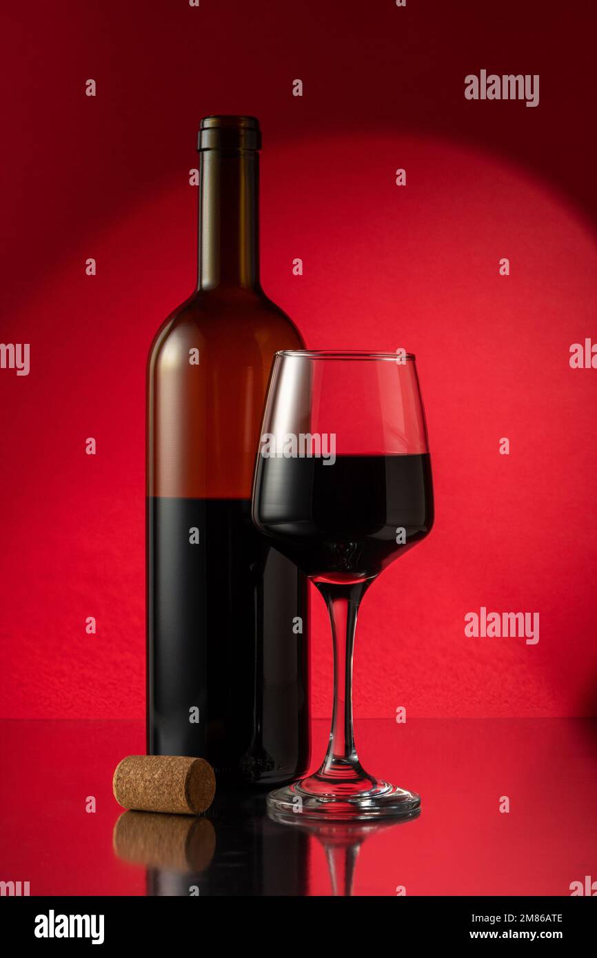 Bottiglia di vino rosso con bicchiere di vino e sughero sul tavolo. Concetto di bevanda. Foto Stock