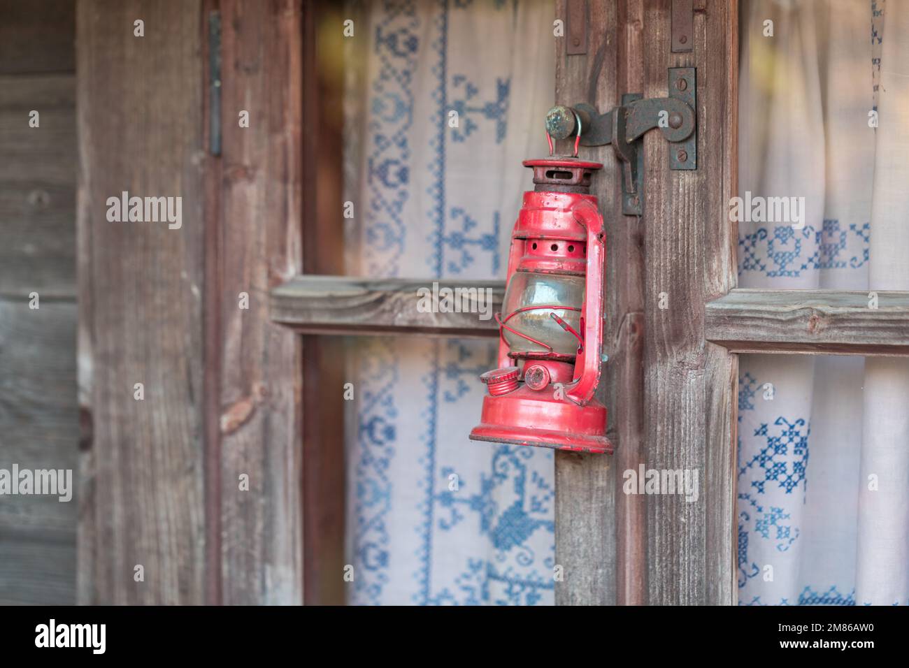 Una vecchia lampada a cherosene appesa ad una trave o finestra di legno. Foto Stock
