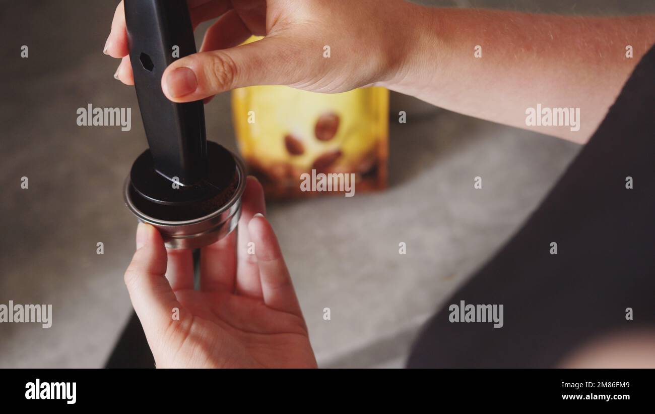 donna con portafiltro e caffè pressato, confezione di caffè sullo sfondo. Foto di alta qualità Foto Stock