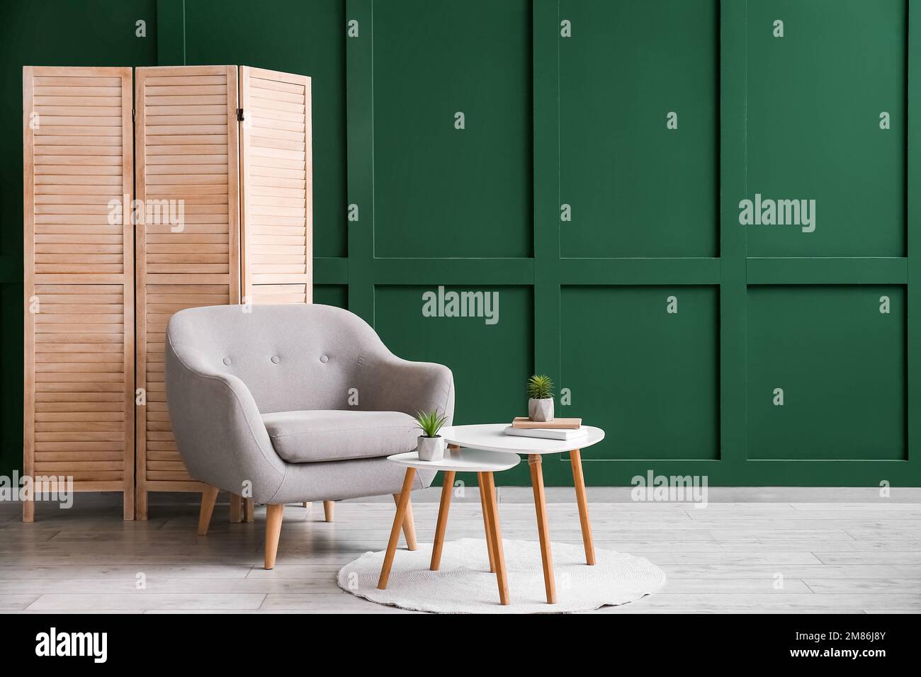 Interno del soggiorno con schermo pieghevole, poltrona e tavolino vicino  alla parete verde Foto stock - Alamy