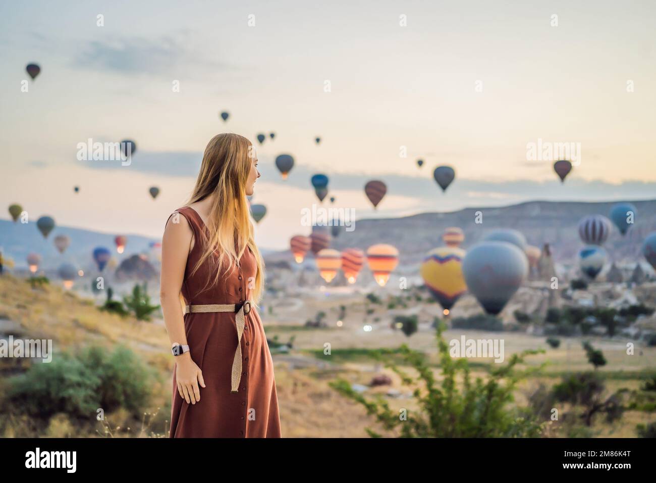 Donna turistica che guarda mongolfiere in Cappadocia, Turchia. Buon viaggio in Turchia concetto. Donna in cima a una montagna che gode di una vista meravigliosa Foto Stock