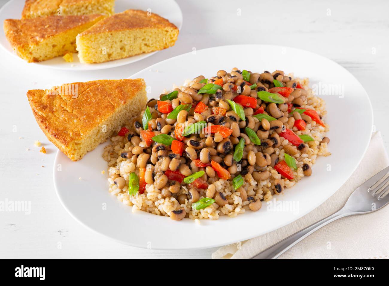 Versione vegana di John Hoppin con pane di mais in un piatto bianco con pane di mais sul lato Foto Stock